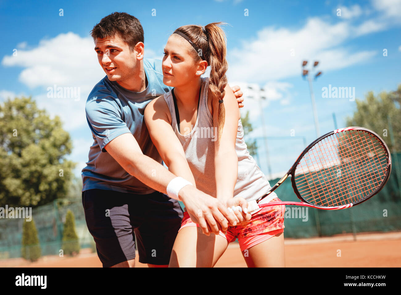 Beautiful young woman with instructor practicing tennis on dross court. Stock Photo