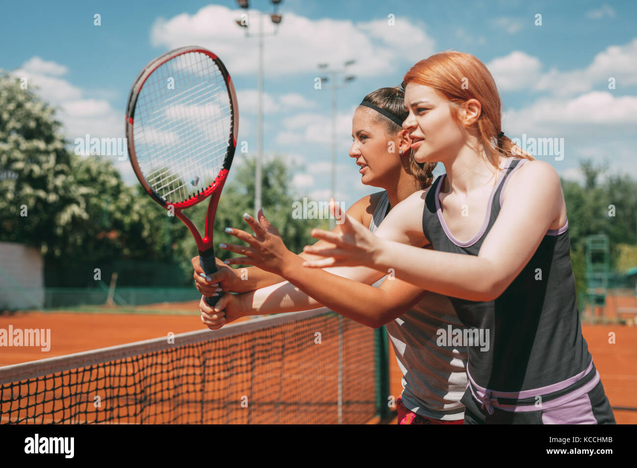 Beautiful young woman with female instructor practicing tennis on dross court. Stock Photo