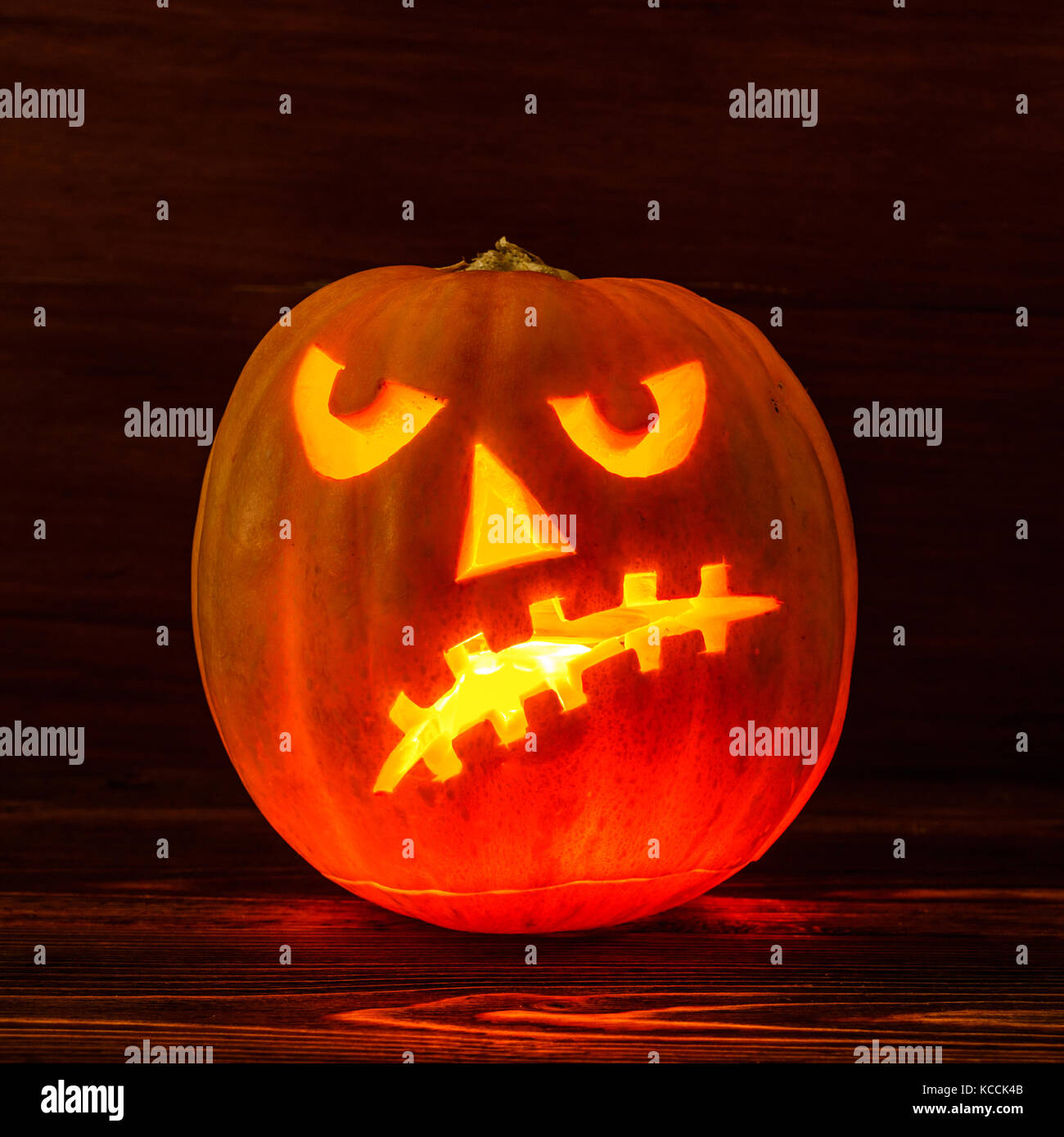 Scary Halloween pumpkin isolated on a wooden background . Scary glowing face trick or treat. Concept of halloween pumpkin on wooden planks. Stock Photo