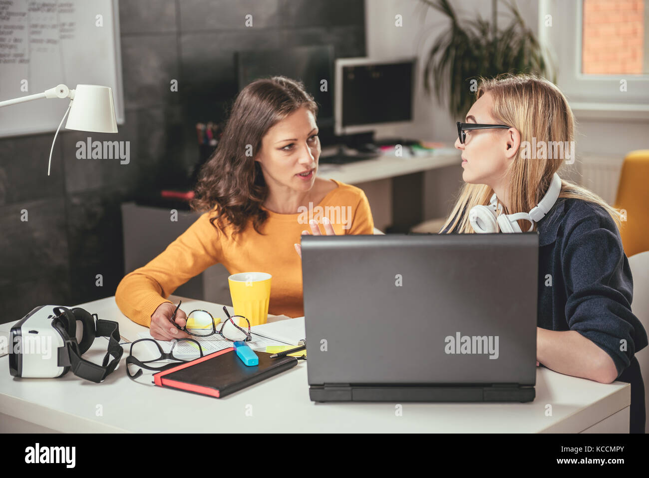 Two business woman using computer at the office and discussing Stock Photo