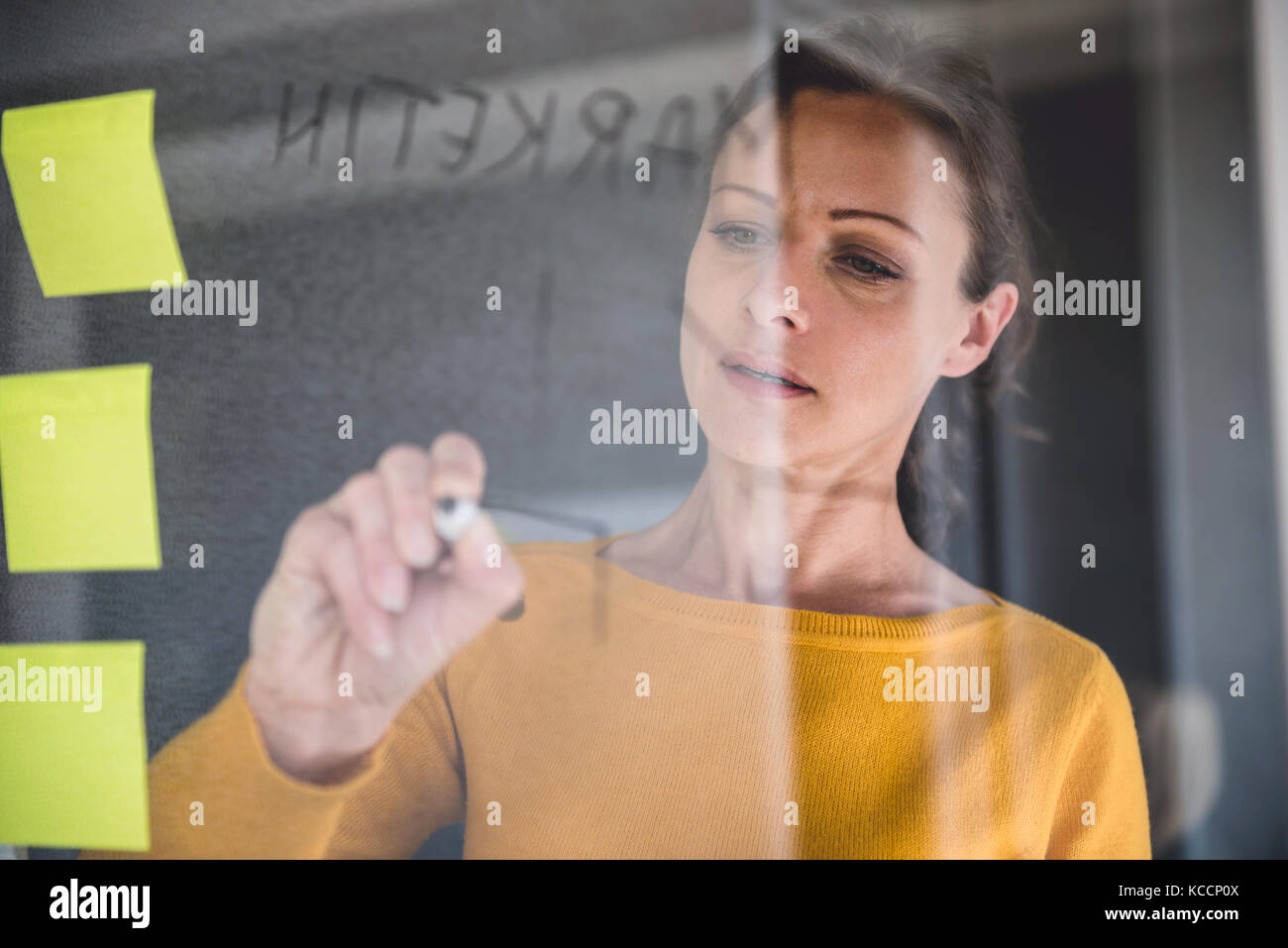 Woman writing notes on the glass board at the office Stock Photo