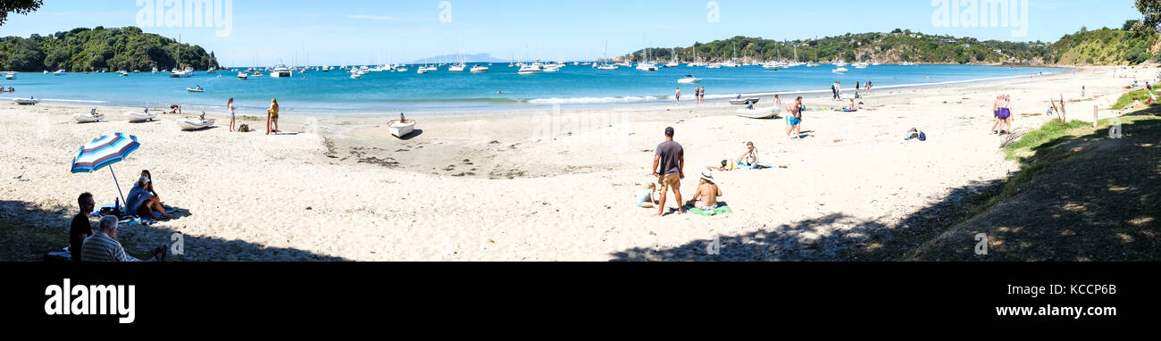 Oneroa, Waiheke Islands, New Zealand, NZ - February 4, 2017 - Panorama of people on the white sand beach plus a busy anchorage with many boats Stock Photo