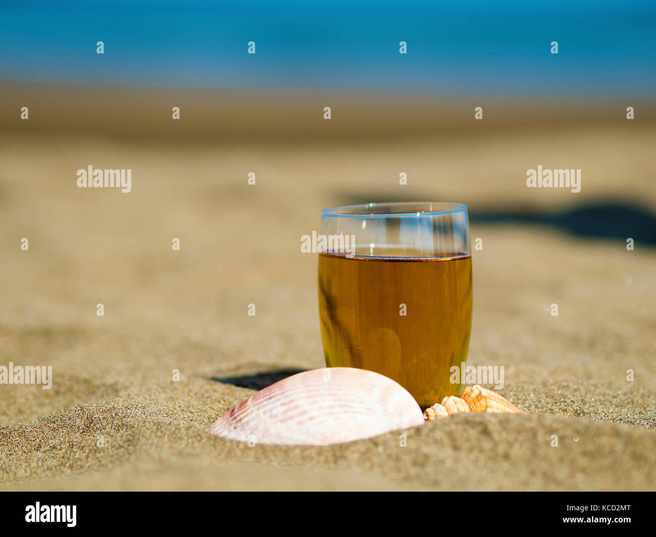 glass of tea with shells on summer beach Stock Photo