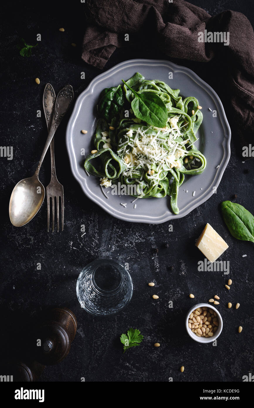 Green spinach pasta with cheese and pine nuts. Top view, dark food photo. Vertical. Homemade healthy green pasta Stock Photo