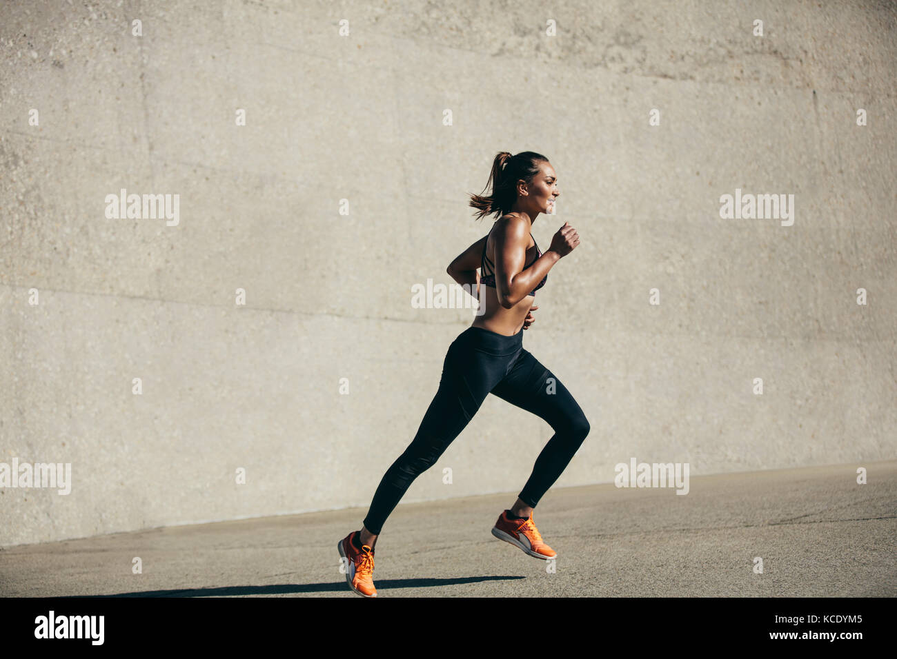 Healthy young woman running in morning. fitness model exercising in morning outdoors. Full length side view shot. Stock Photo