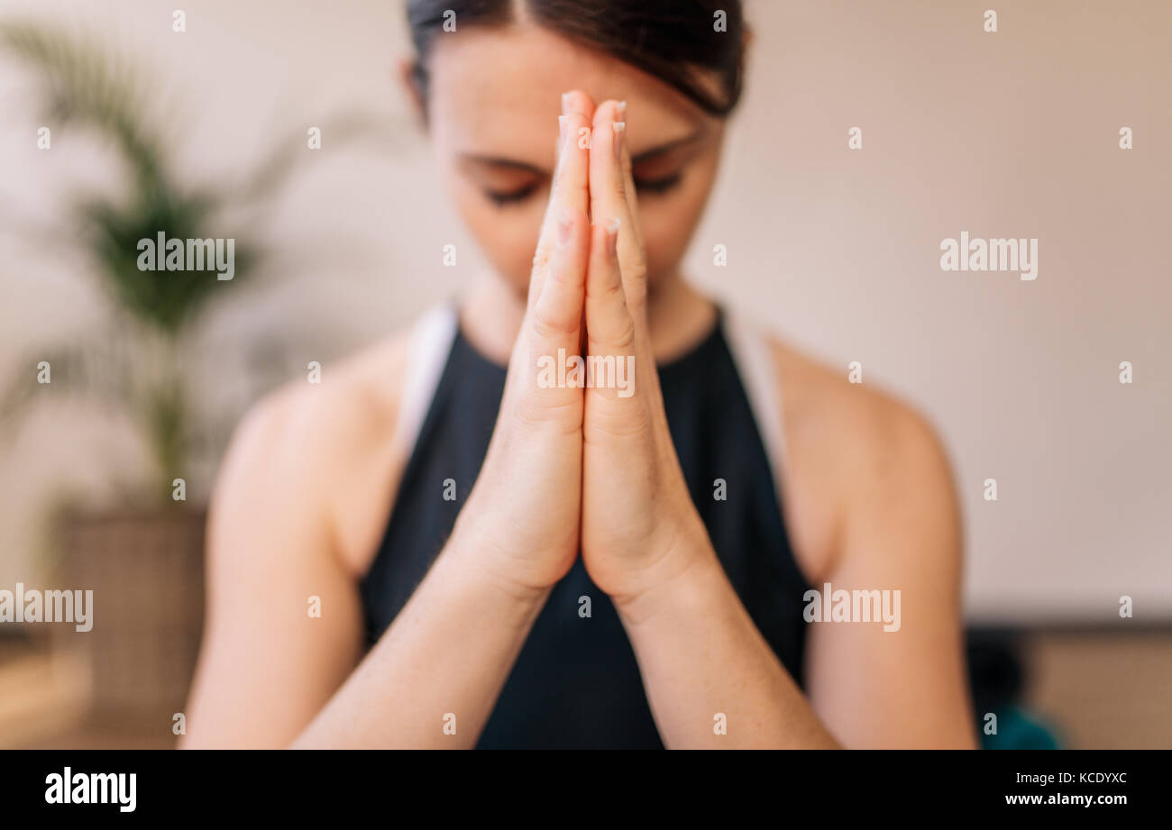 Close up of woman hands joined. Female meditating with her hands joined indoors. Namaste yoga pose, meditating, breathing and relaxing. Stock Photo