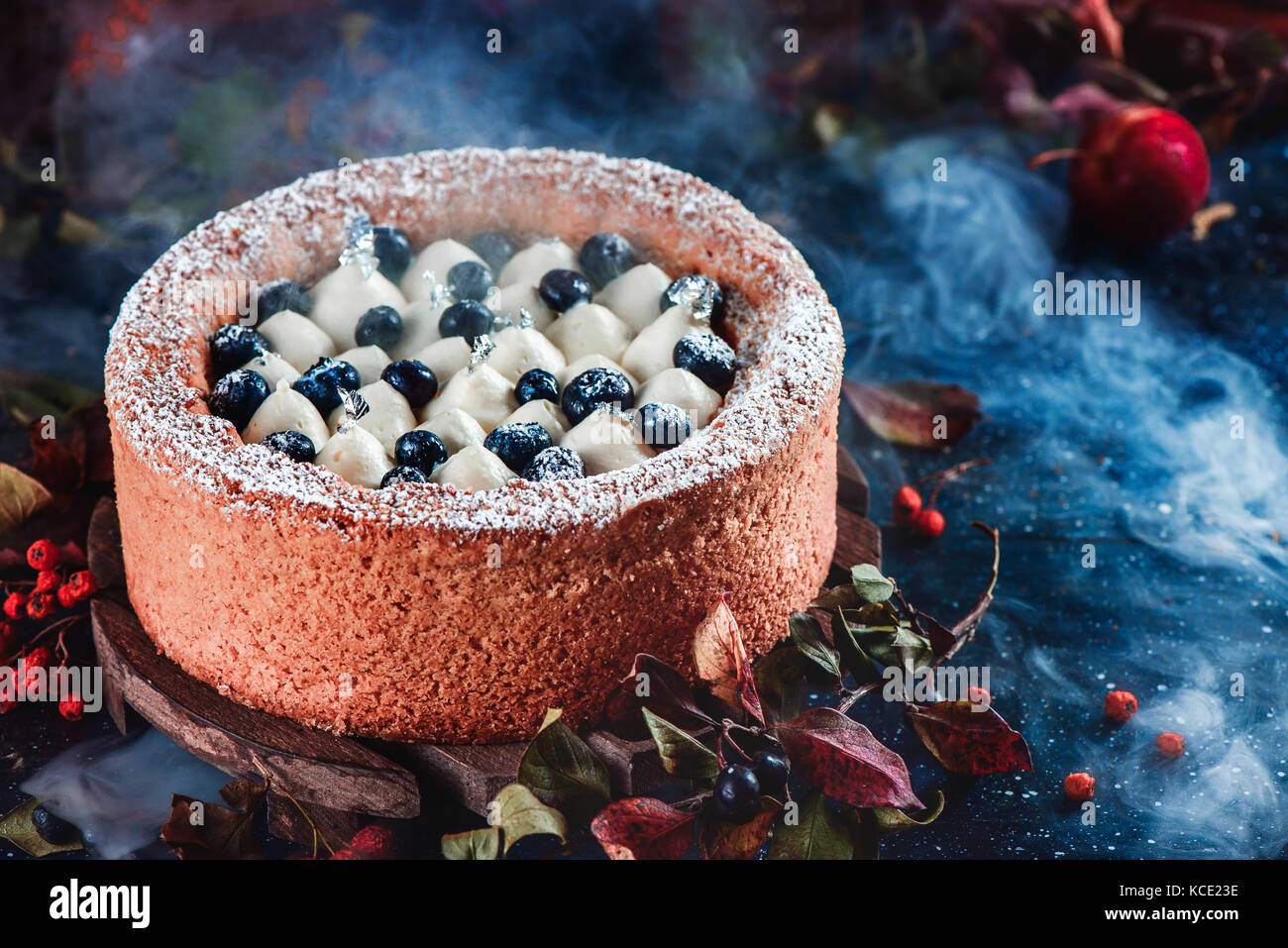 Whipped cream and blueberry cake with a shortbread crust on a dark background. Dark food photography with smoke. Traditional pumpkin pie in a Halloween still life with pastry. Stock Photo