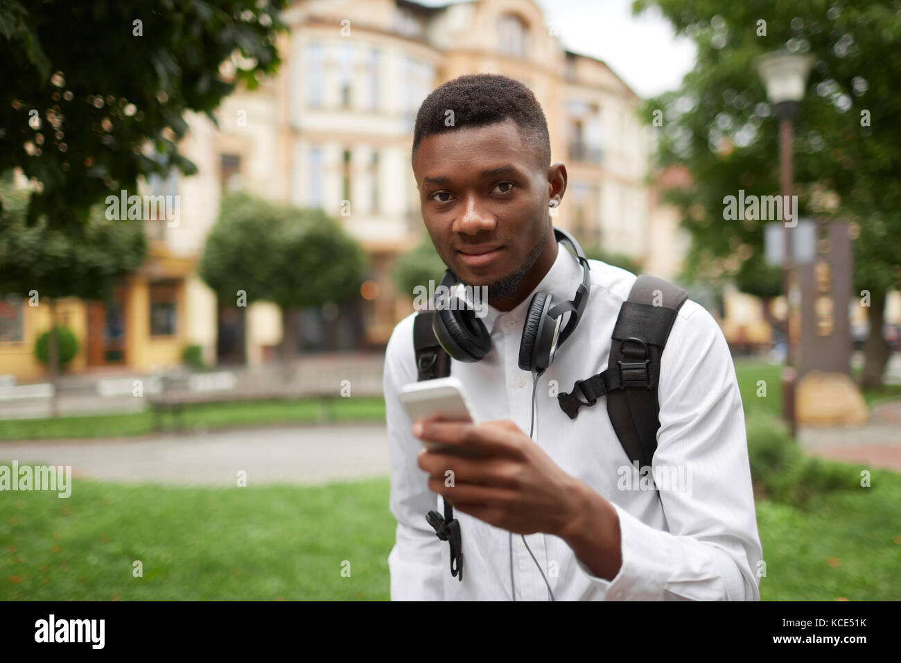 African student chatting, writing message with smart phone. Stock Photo