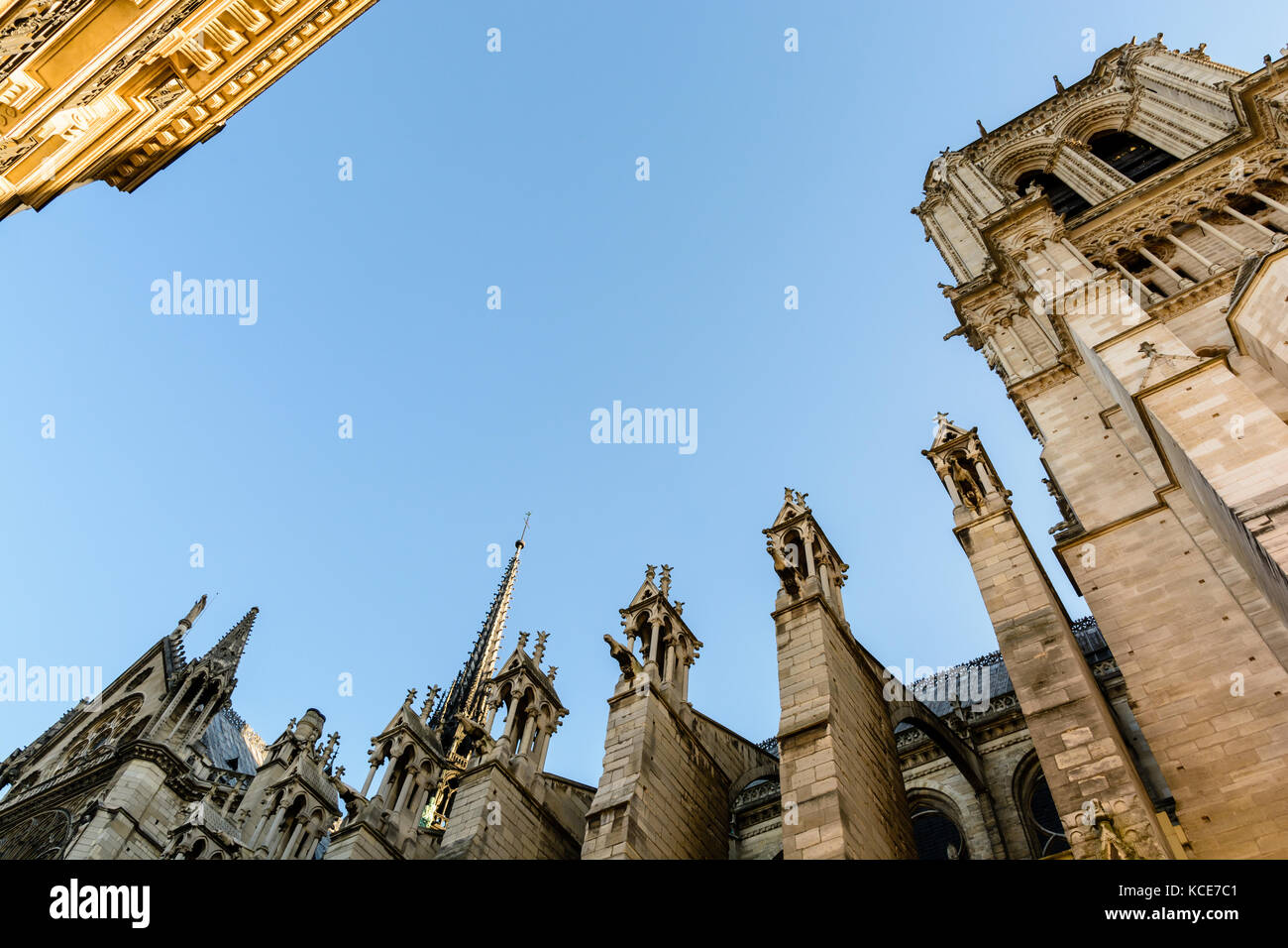 Low angle view of the North side and spire of Notre-Dame de Paris cathedral at sunset facing a residential building in the sunlight. Stock Photo