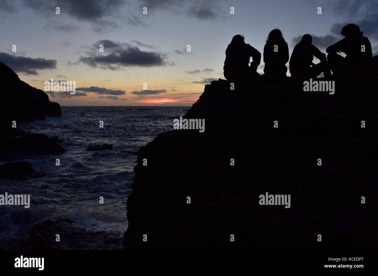Dusk at Droskyn Point, Perranporth, Cornwall, with four people silhouetted in the dusk. Stock Photo