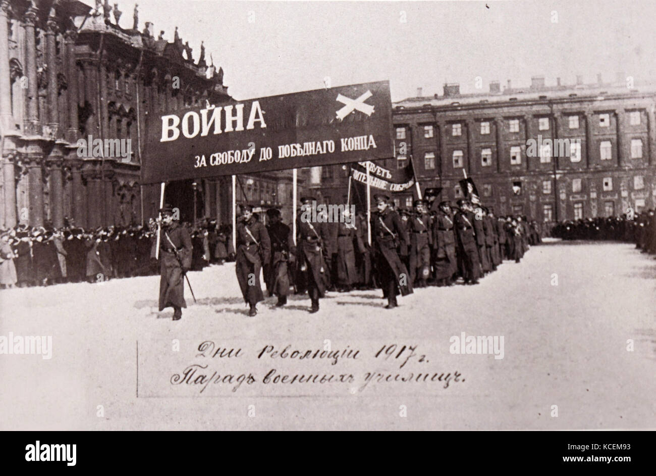 Photograph of Russian soldiers marching past the Winter Palace in Petrograd. The soldiers are carrying a banner which translates to 'On with War for Liberty'. Dated 20th Century Stock Photo