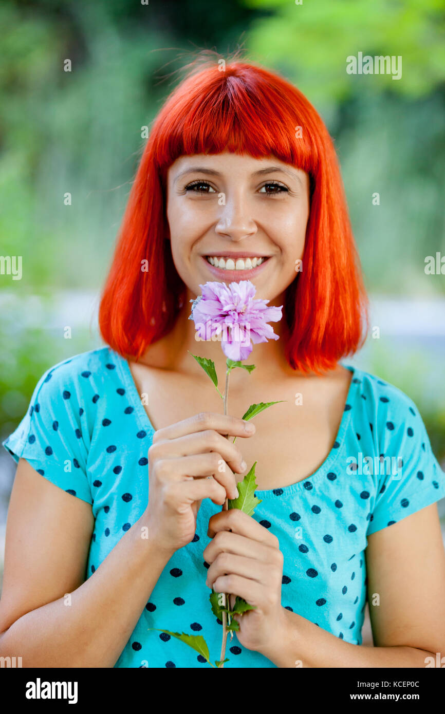 Redhead woman smelling a flower in a beautiful park Stock Photo - Alamy
