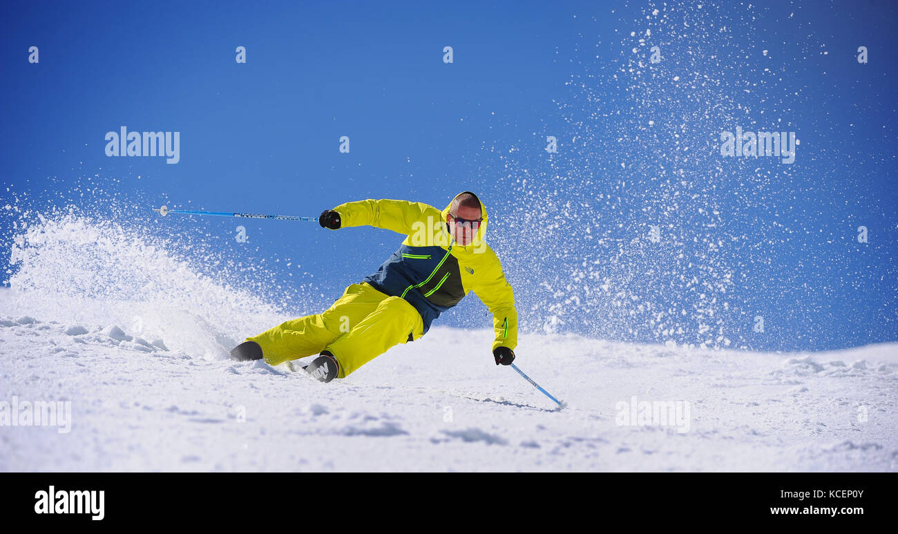 A skier carves a turn sending snow spraying into the air in the French ski resort of Courchevel. Stock Photo