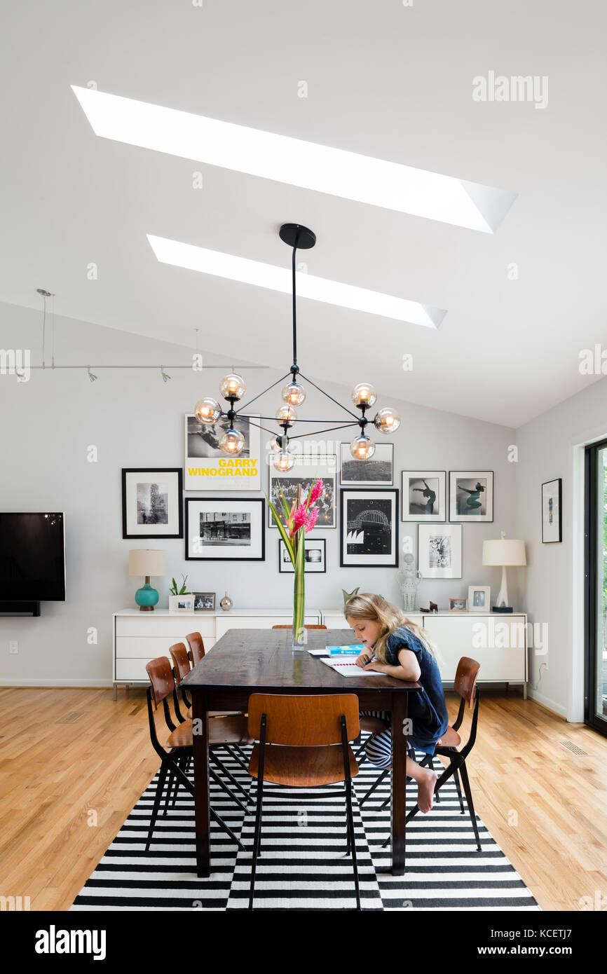 Girl sitting at the dining table in the main living room. editorial use only. Bruning Owen House, Chevy Chase, United States. Architect: Lou Balodemas Stock Photo