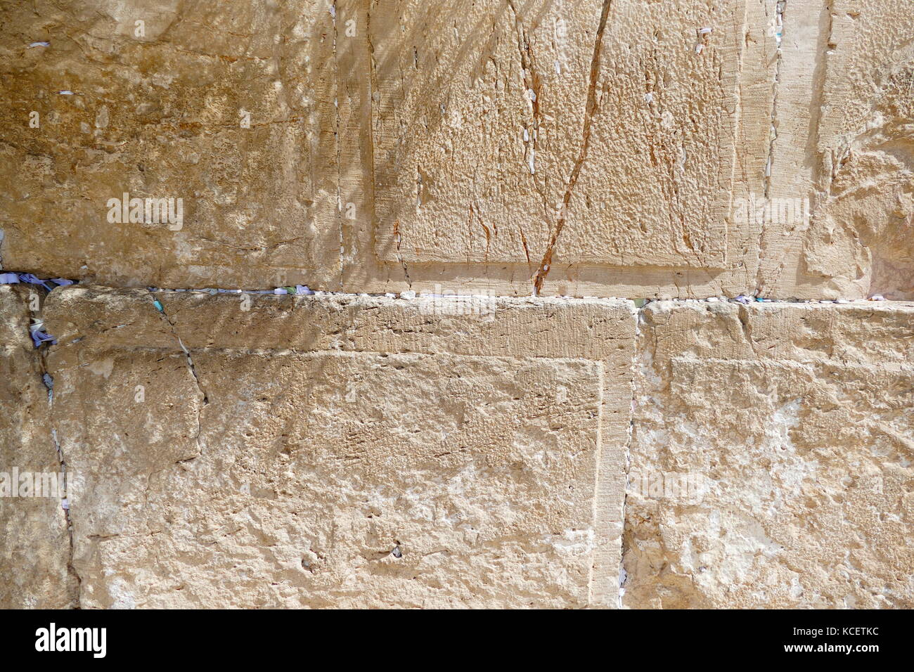 Slips of paper containing prayers in the cracks of the Western Wall (Ha-Kotel Ha-Ma'aravi) in Jerusalem. The Wall is the holiest of Jewish sites, sacred because it is a remnant of the Herodian retaining wall that once enclosed and supported the Second Temple. It has also been called the 'Wailing Wall' Stock Photo