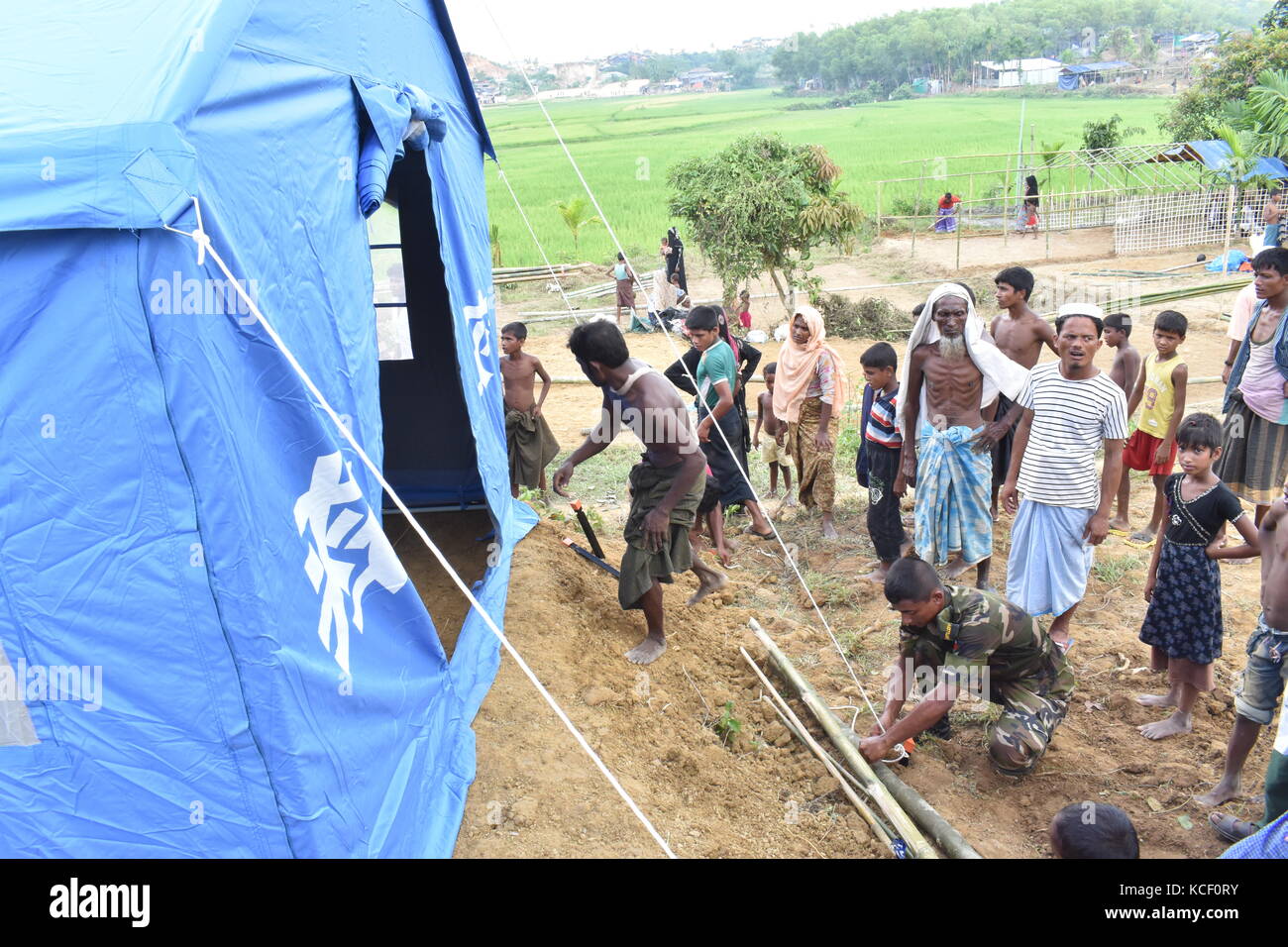 (171004) -- DHAKA, Oct. 4, 2017 (Xinhua) -- An Army personnel helps a Rohingya family to set up Chinese relief tent at a camp in Cox's Bazaar district, Bangladesh, on Oct. 3, 2017. China has sent relief supplies for Rohingya refugees in Bangladesh recently. (Xinhua/Jibon Ahsan) (zcc) Stock Photo