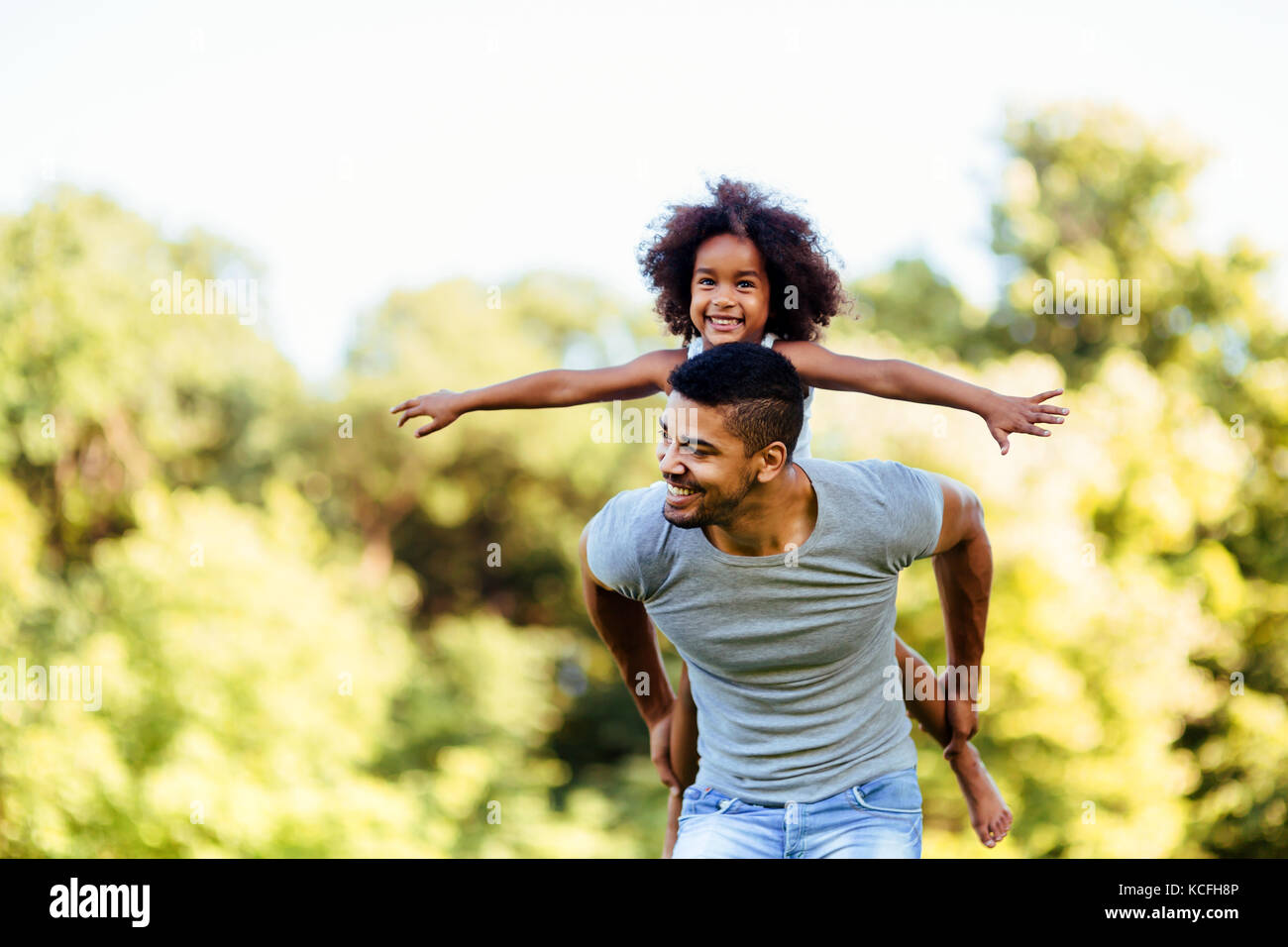 Portrait of young father carrying his daughter on his back Stock Photo