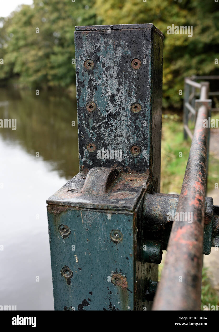 Metal gear housing attached to hand rail at the side of the river Irwel withsoft focus blurred river and trees, Burrs country park bury lancashire uk Stock Photo