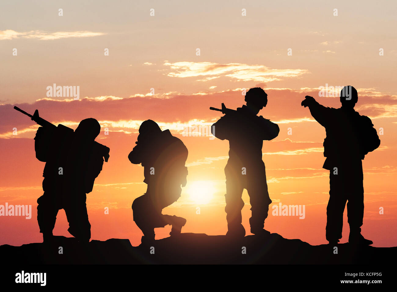 Silhouette Of Soldiers Armed With Weapons Against Climatic Sky On Battlefield Stock Photo