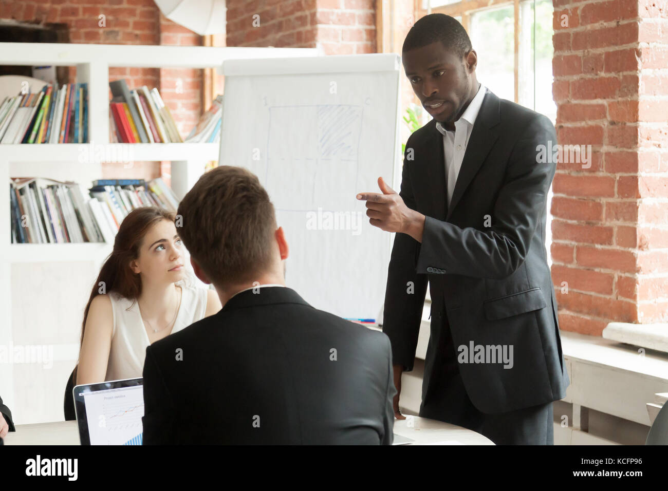 African American employee behaving rudely during briefing meeting. Disgruntled corporate worker expressing frustration to his coworkers. Angry busines Stock Photo