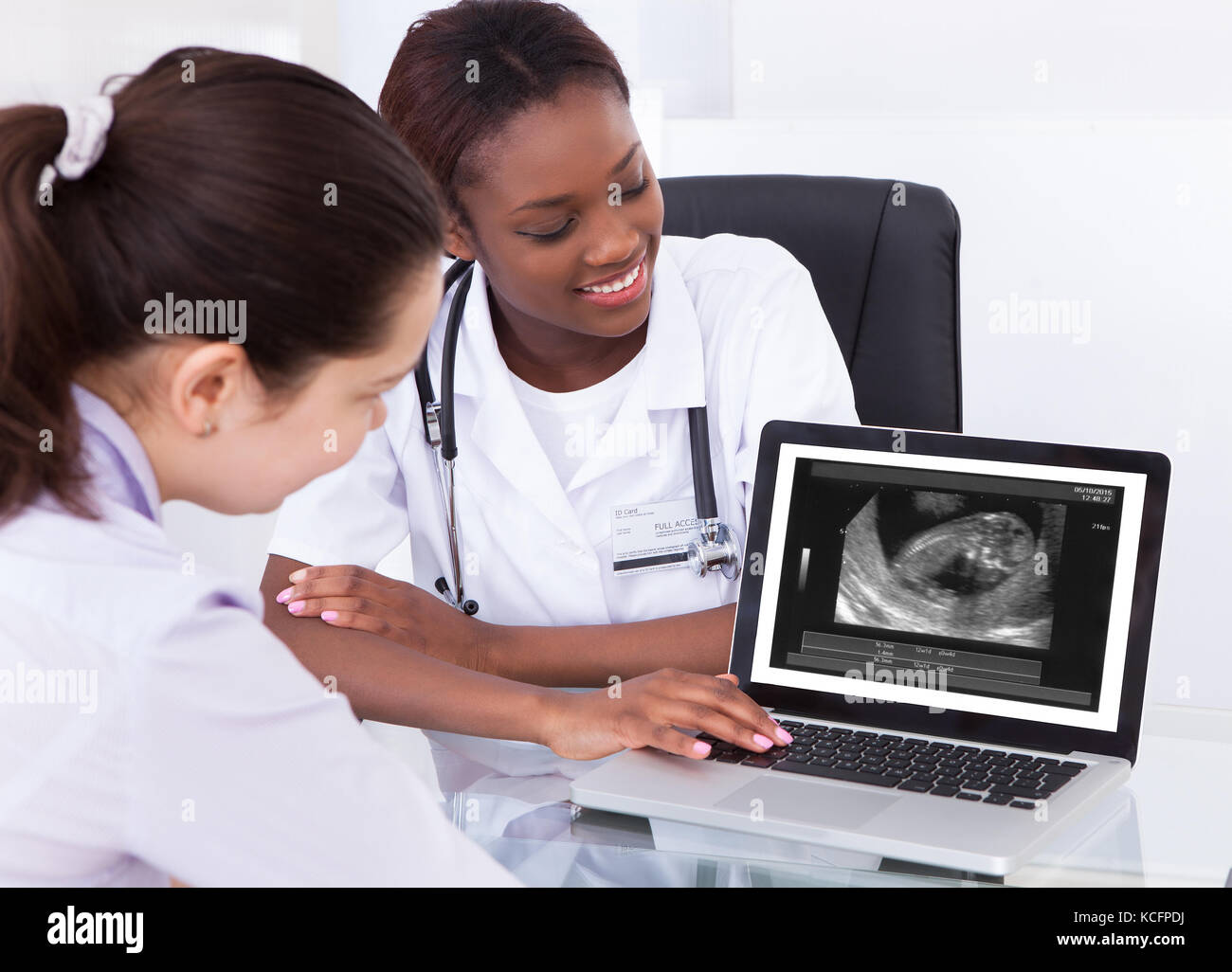 Happy Female Doctor Showing Ultrasound Scan Of Baby On Laptop To Her Patient At Clinic Stock Photo
