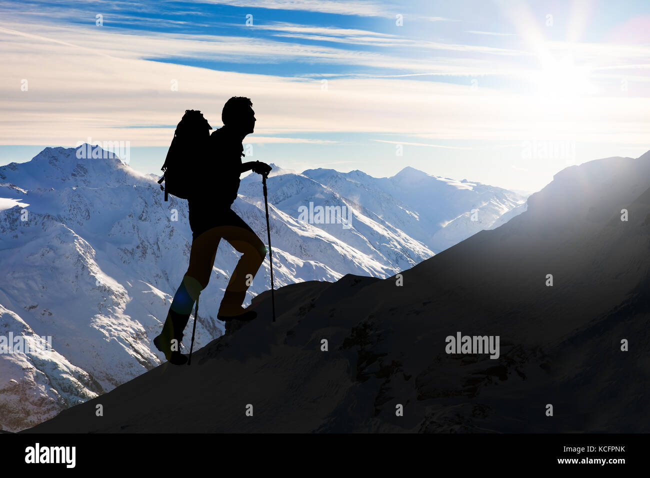 Silhouette Of A Man With Backpack And Hiking On A Mountain Stock Photo