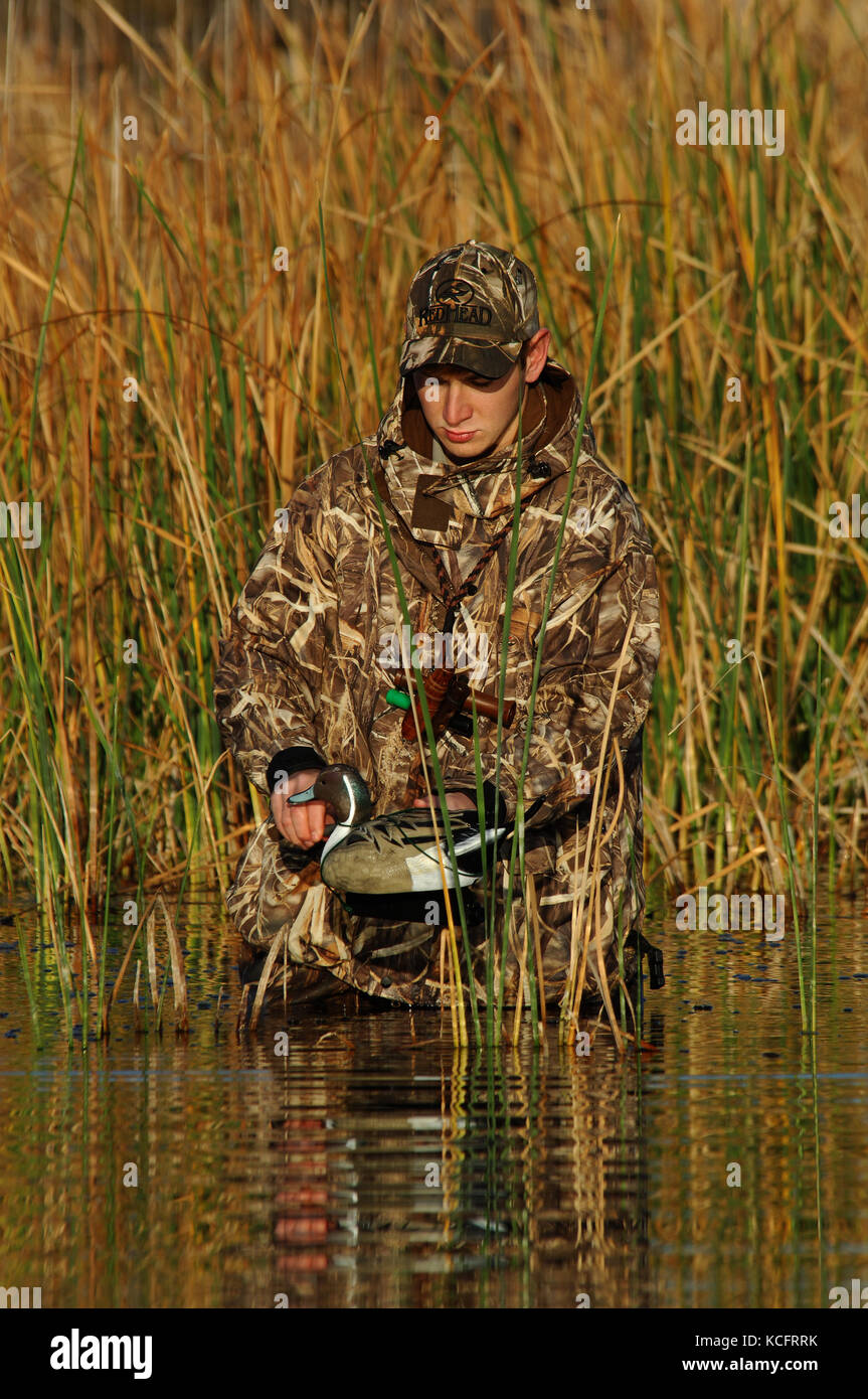 A duck hunter in camouflage sets out his hunting decoys in a South