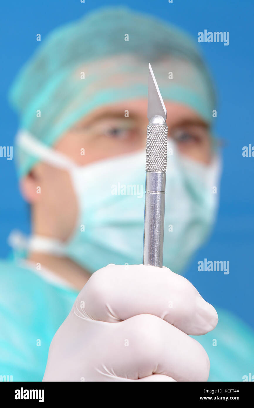 Closeup of surgeon holding scalpel up his face over blue background Stock Photo