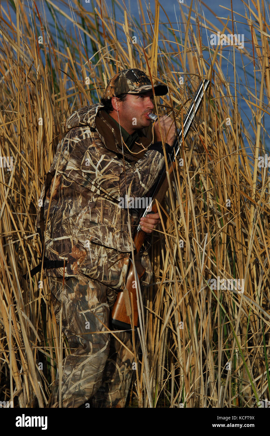 A duck hunter in camouflage calls ducks from a marsh in South Texas