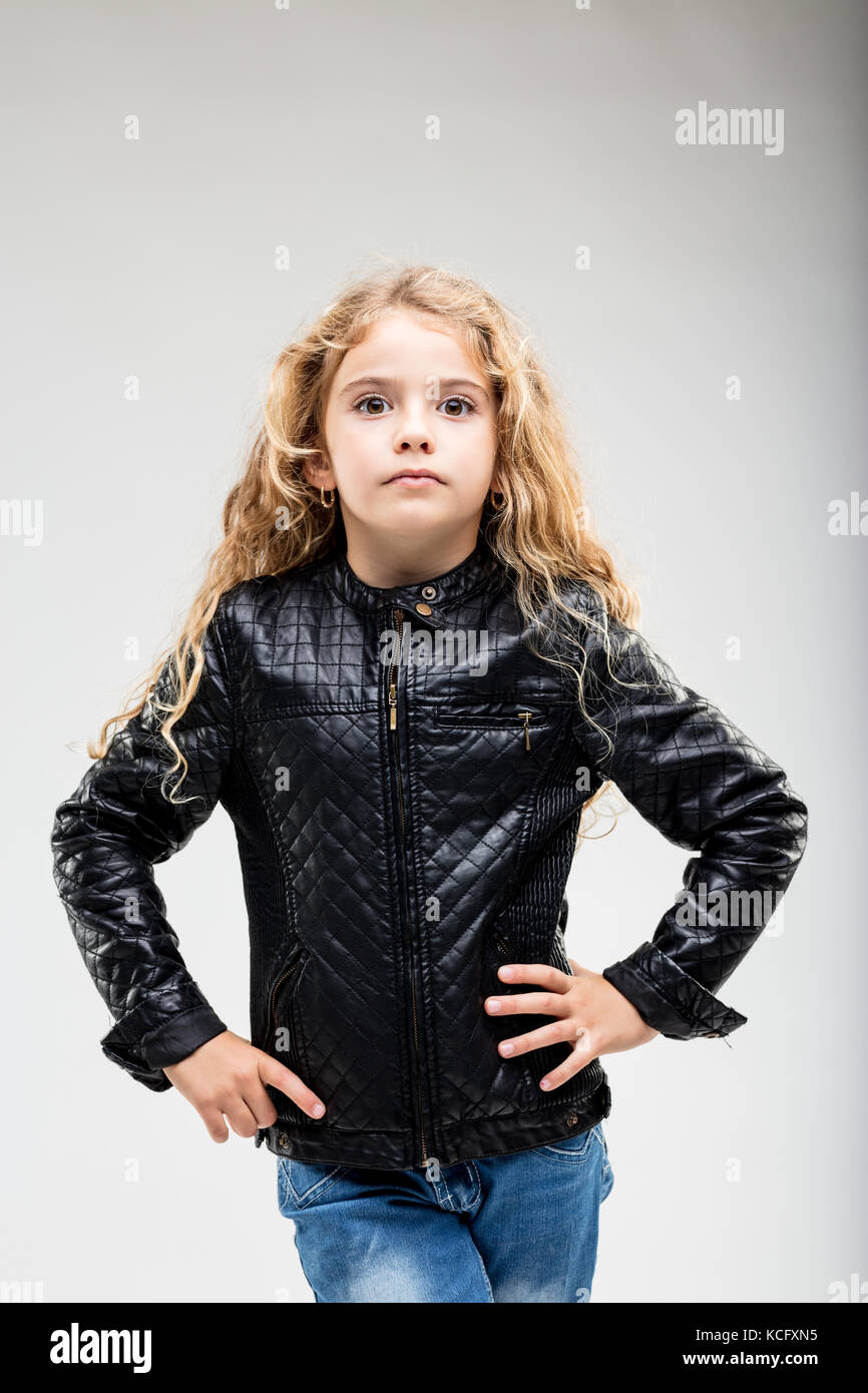 Curly-haired serious preteen girl wearing leather jacket posing against ...