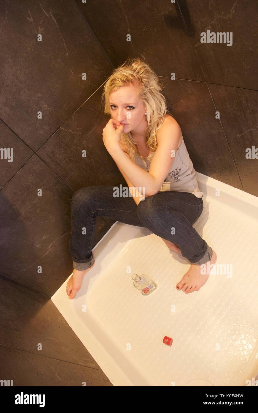 Girl showing signs of depression and mental illness in a shower Stock