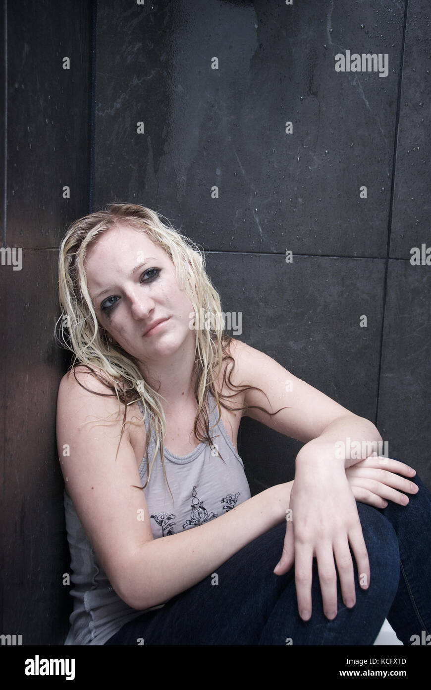 Girl showing signs of depression and mental illness in a shower Stock