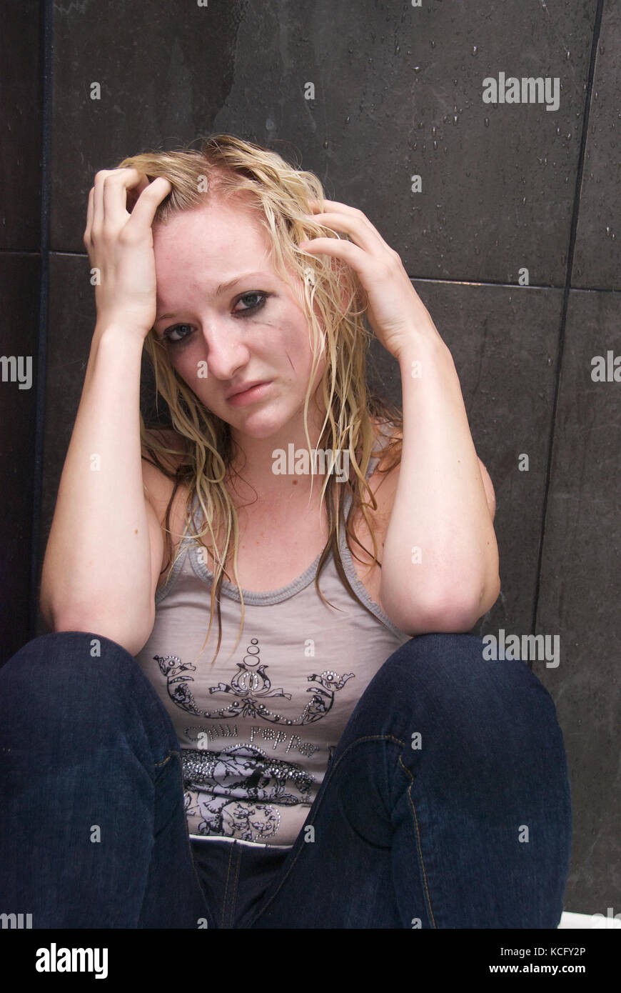 Girl showing signs of depression and mental illness in a shower Stock