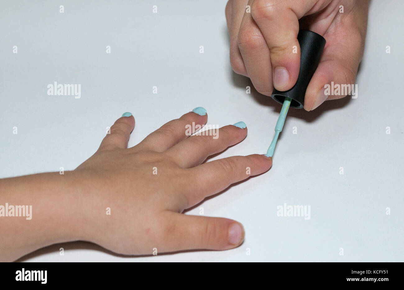 older sister applying nail polish to younger sister Stock Photo