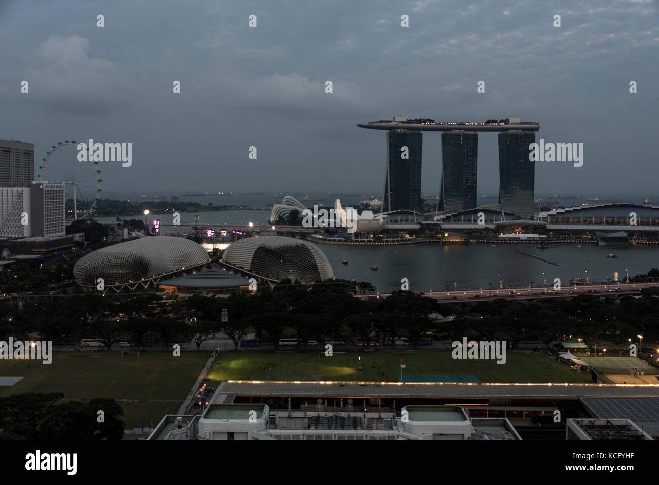 Also, the shell-shaped Esplanade Theatre by the Bay and the Padang.  At dusk over Singapore and Marina Bay. In the foreground is the Padang. Stock Photo