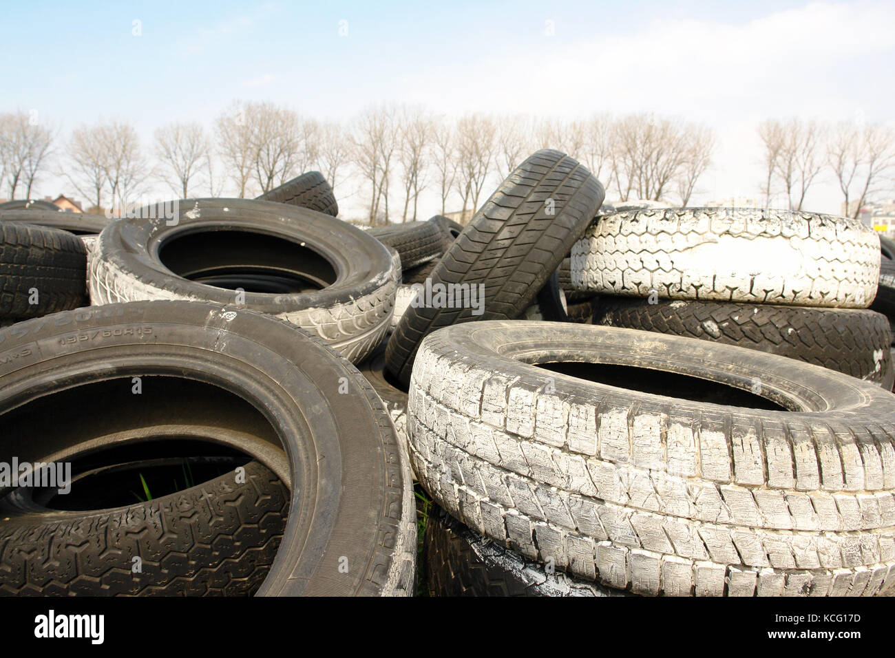 Heap of used car tires with trees in the background Stock Photo