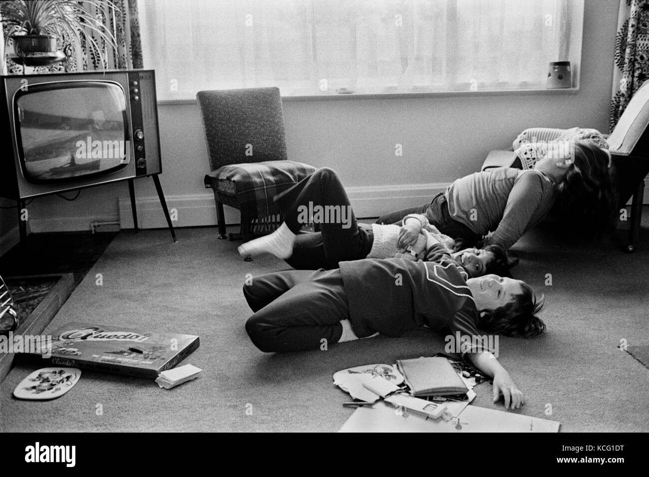 Children playing in living room, watching TV. Board games on the floor. Middle class family home Leicestershire 1970s 1972 England. HOMER SYKES Stock Photo