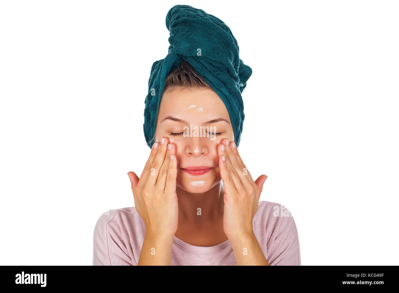 Young woman applying face moisturizer after shower, wearing a towel on