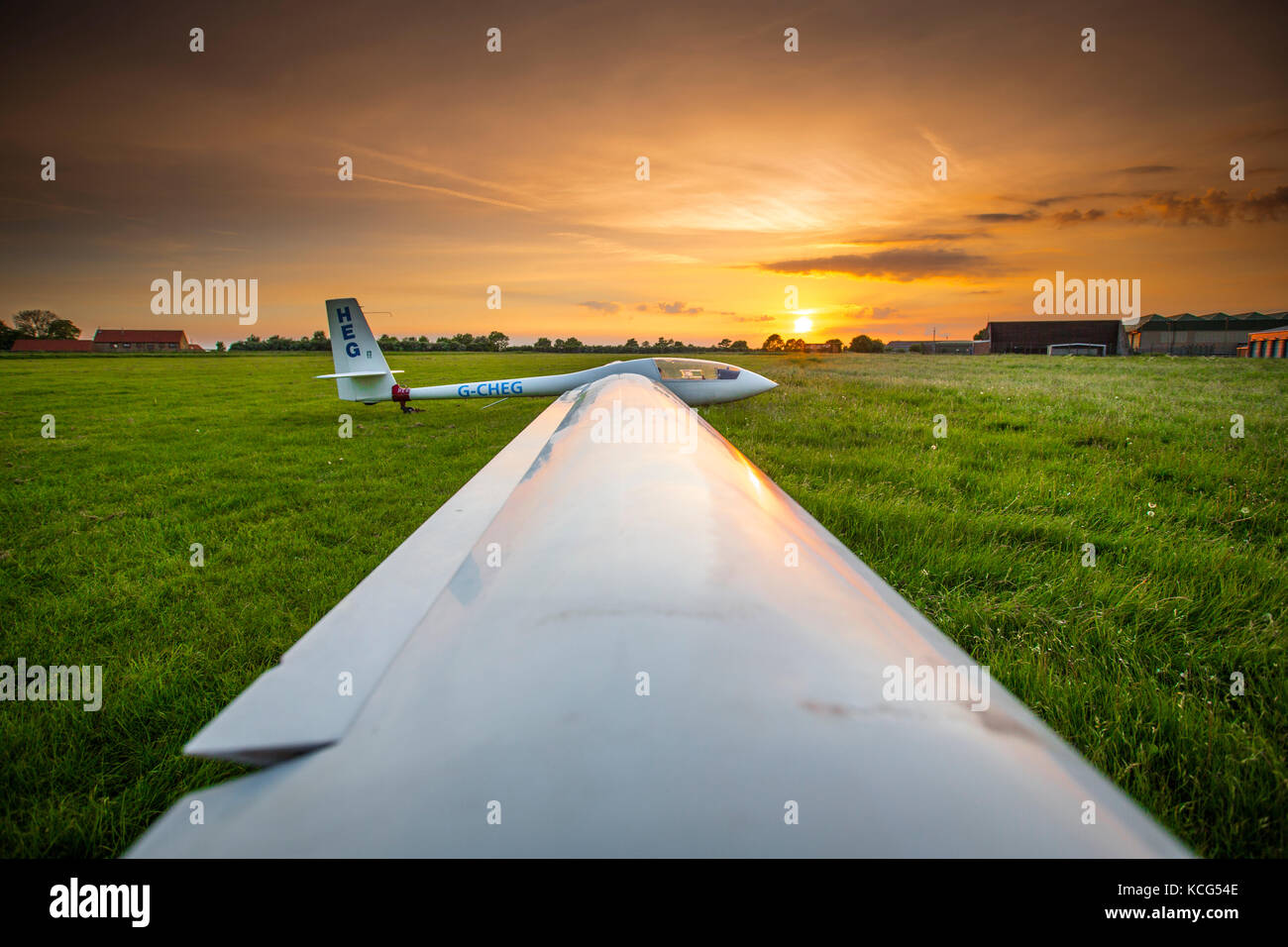 View of an Elan DG-500 Trainer, registration G-CHEG, single seat glider with setting sun at Kirton in Lindsey Airfield, Lincolnshire, UK Stock Photo