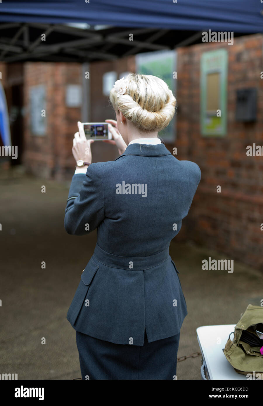 YOUNG WOMEN IN 1940'S VINTAGE RAF UNIFORM TAKING A PHOTO WITH A MOBILE PHONE, UK,2017 Stock Photo