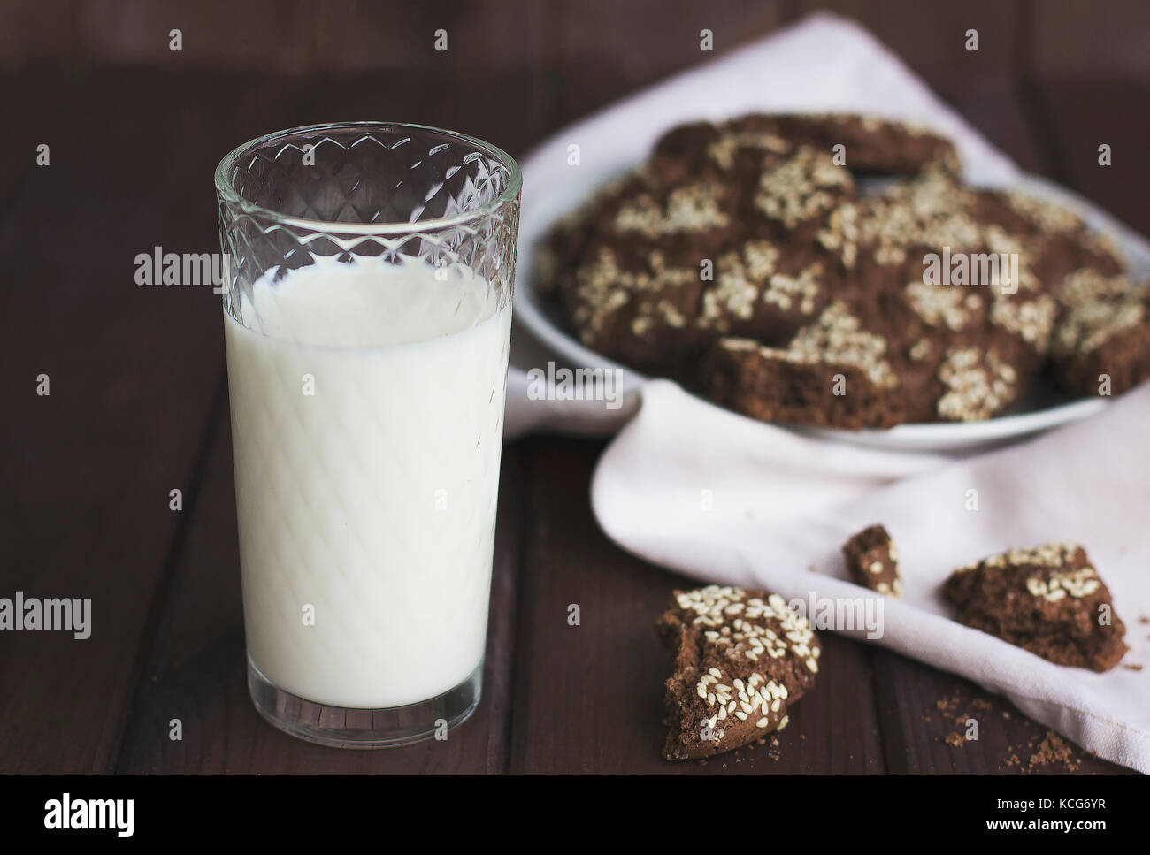 Chocolate cookies with sesame seeds in a vintage plate and a glass of milk  on wooden background Stock Photo - Alamy, image size:1300x967