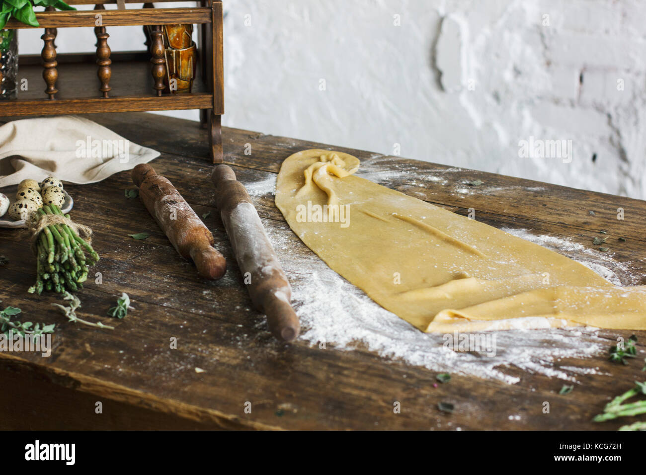 Ingredients for making homemade pasta, rolling pin, quail eggs, asparagus on wooden table Stock Photo