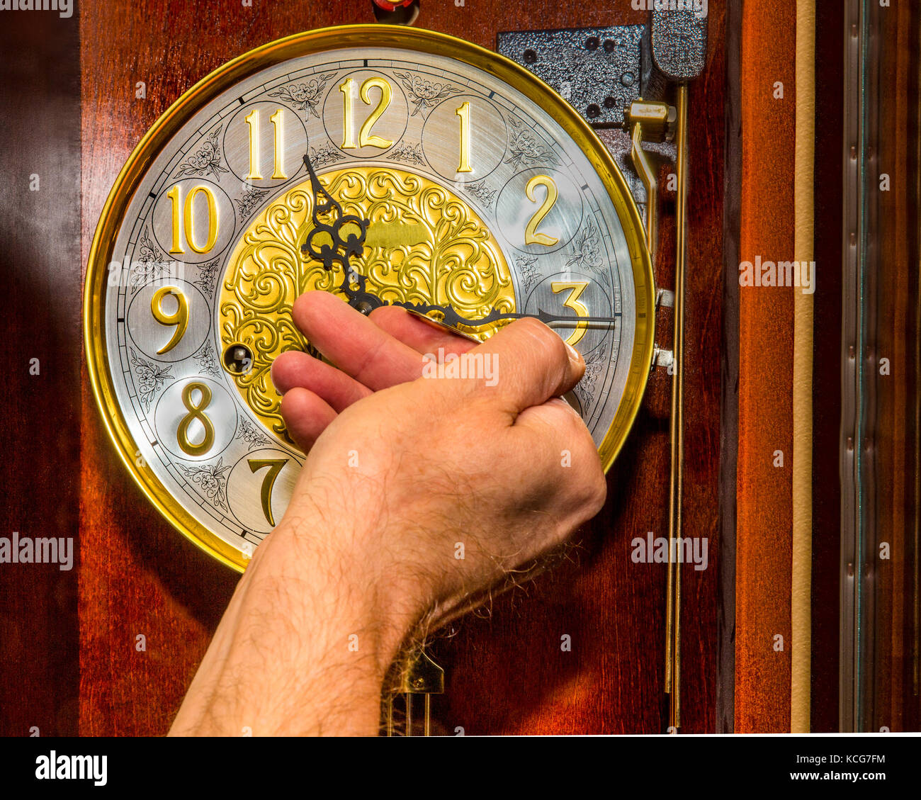 Mans hand winding grandfather clock Stock Photo Alamy