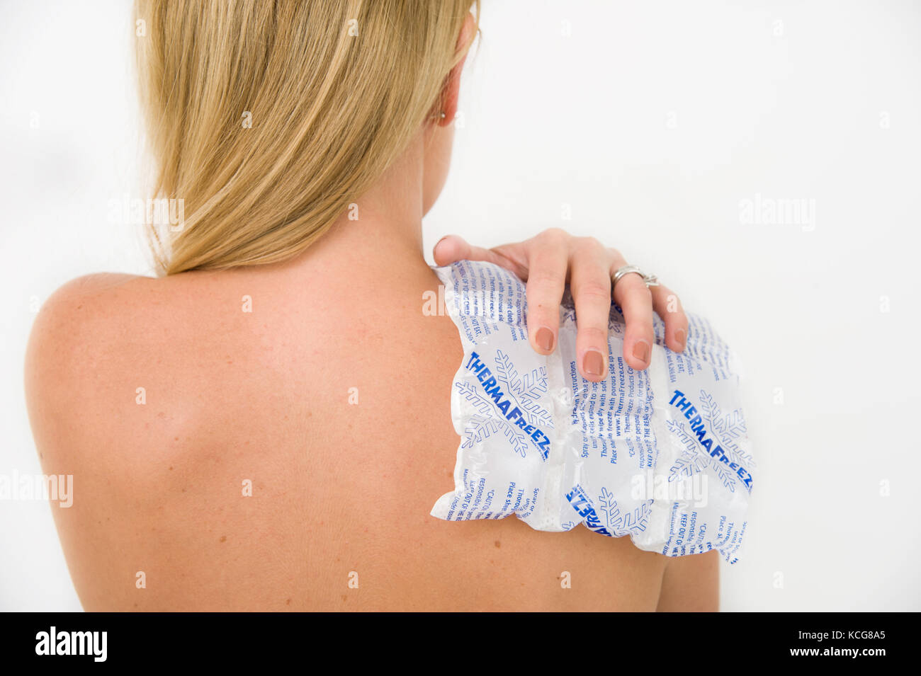 Female holding a Thermafreeze Ice Pack on her Shoulder and back Stock Photo