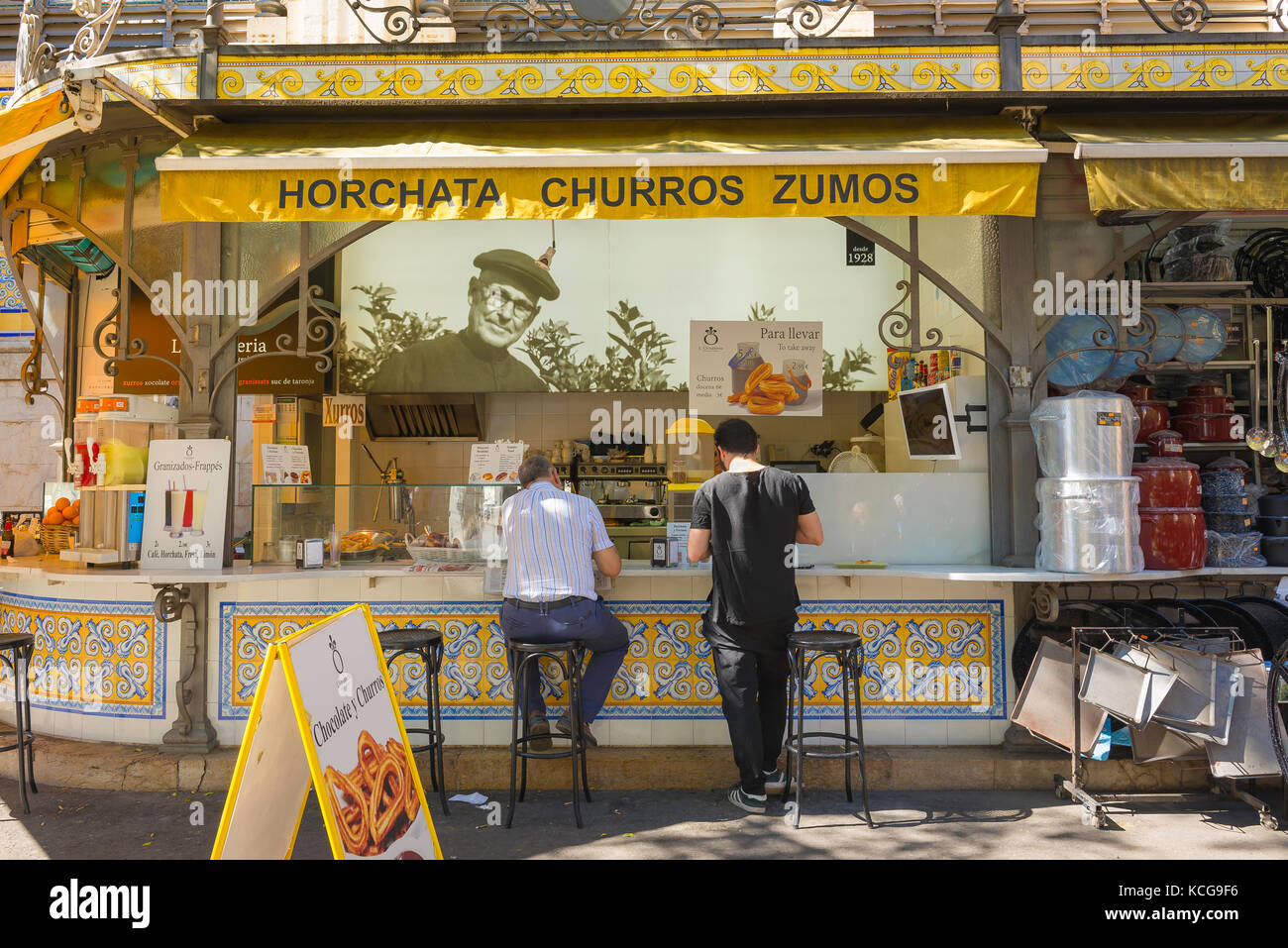 Spain street food, view of two men using a street food kiosk specialising in churros and horchata in the old town district of Valencia, Spain. Stock Photo