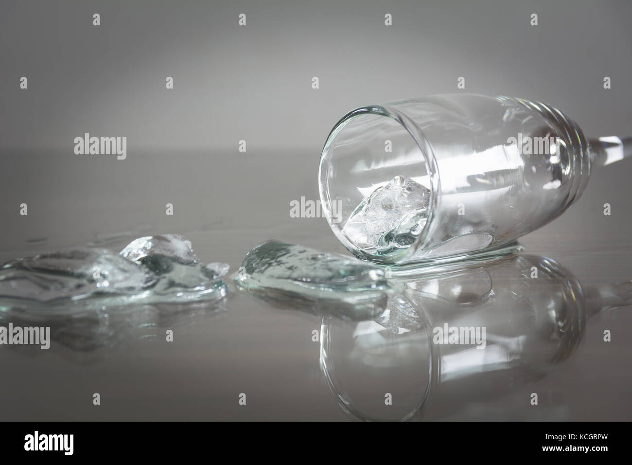 Spilled water with ice cubes on table. Glass with spilled water and ice cube. Stock Photo