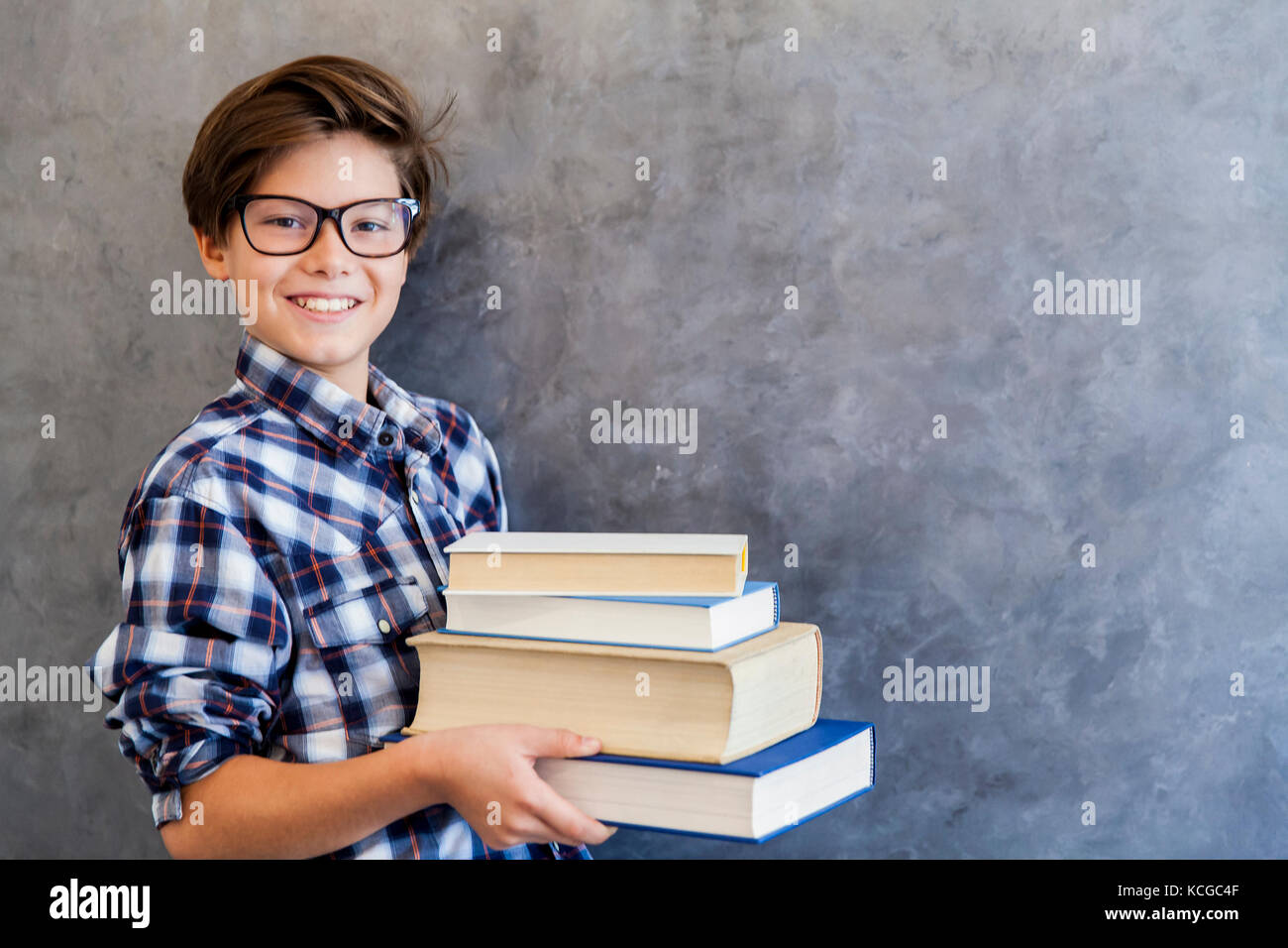 Portrait of teenage school boy with glasses and books by the wall Stock ...