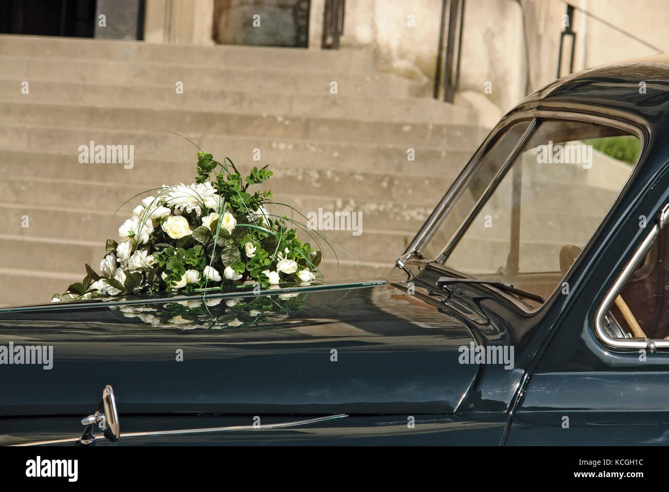 Wedding flowers on retro car parked in front of church building Stock Photo