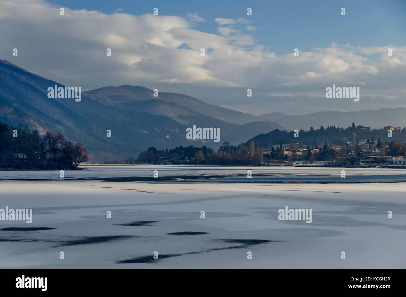 Scene with frozen lake, snowy mountain, glade, forest and residential district of bulgarian village Pancharevo, Sofia, Bulgaria Stock Photo
