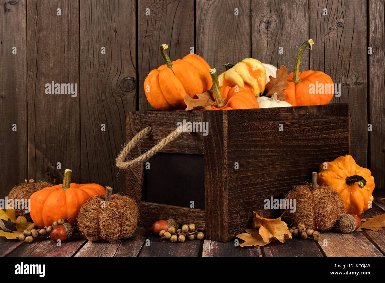 Autumn arrangement with wooden crate of pumpkins and gourds against a rustic wood background Stock Photo